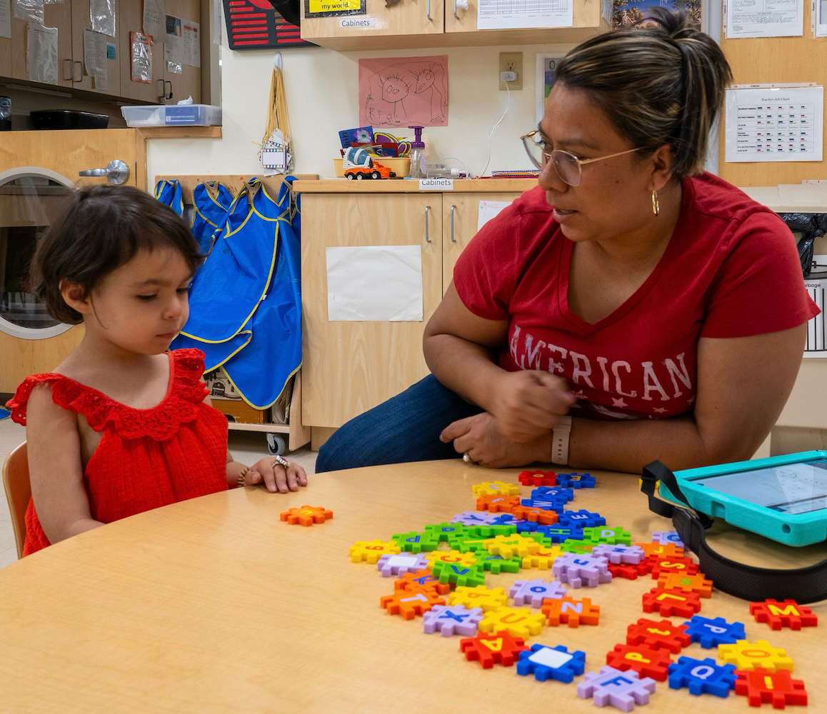 Child and Teacher Playing with Puzzle Pieces