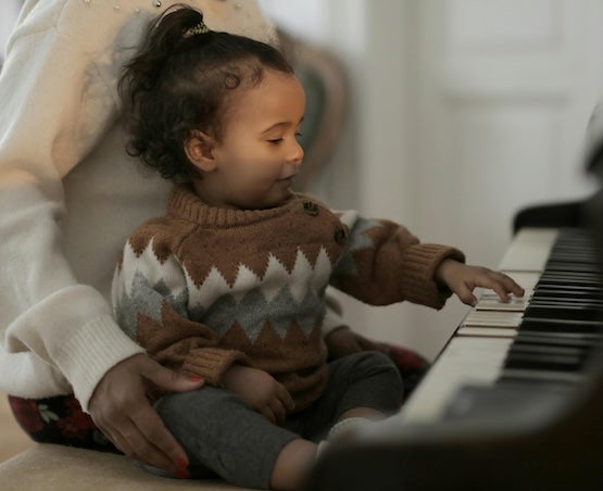 Young girl with adult playing a piano