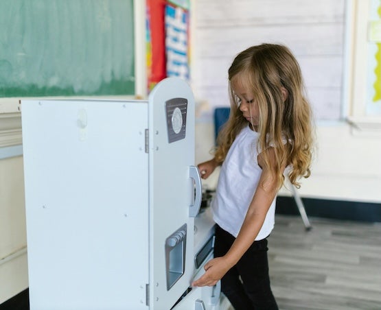 Girl using refrigerator in toy kitchen set