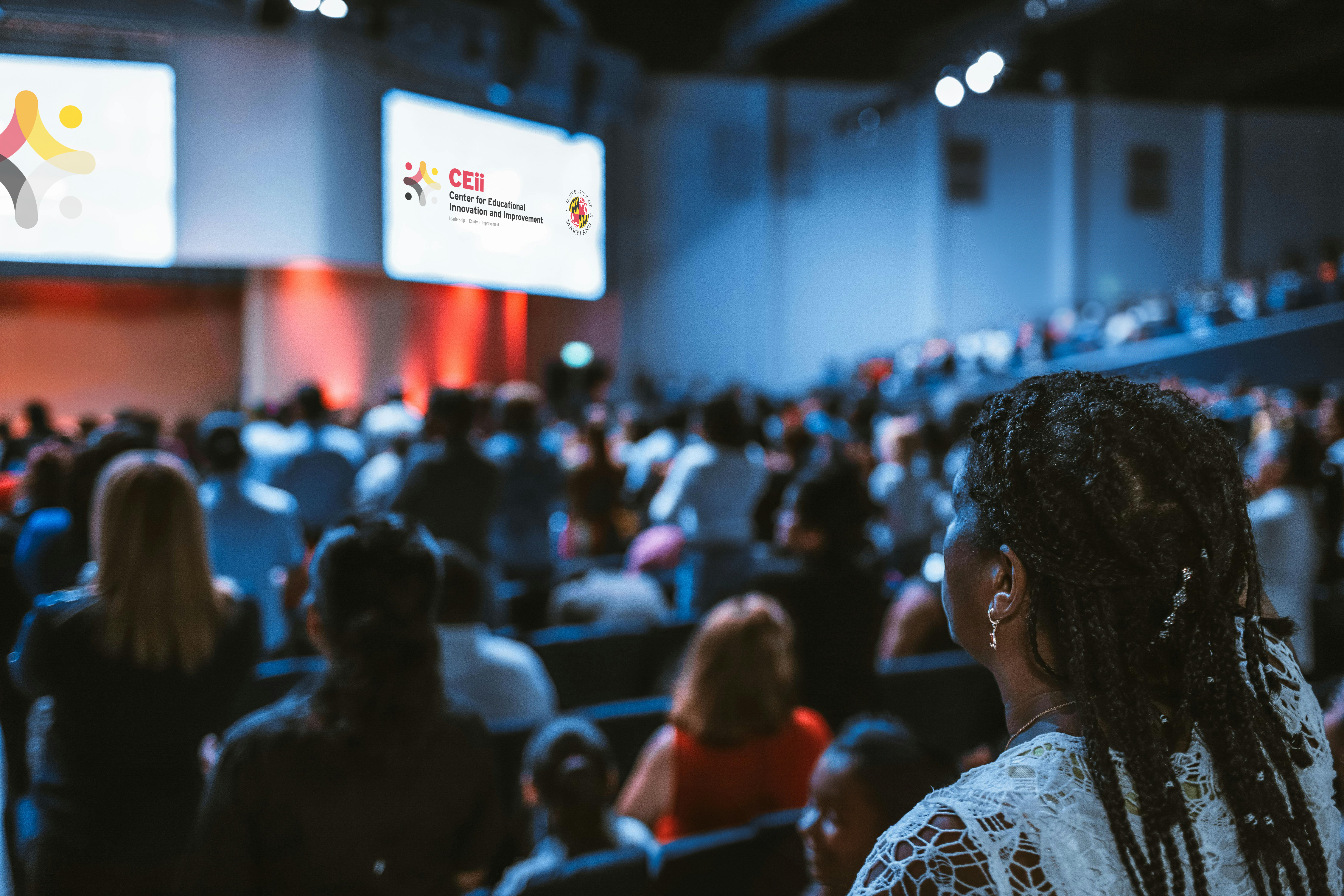 Woman in auditorium looking at screens with CEii logo