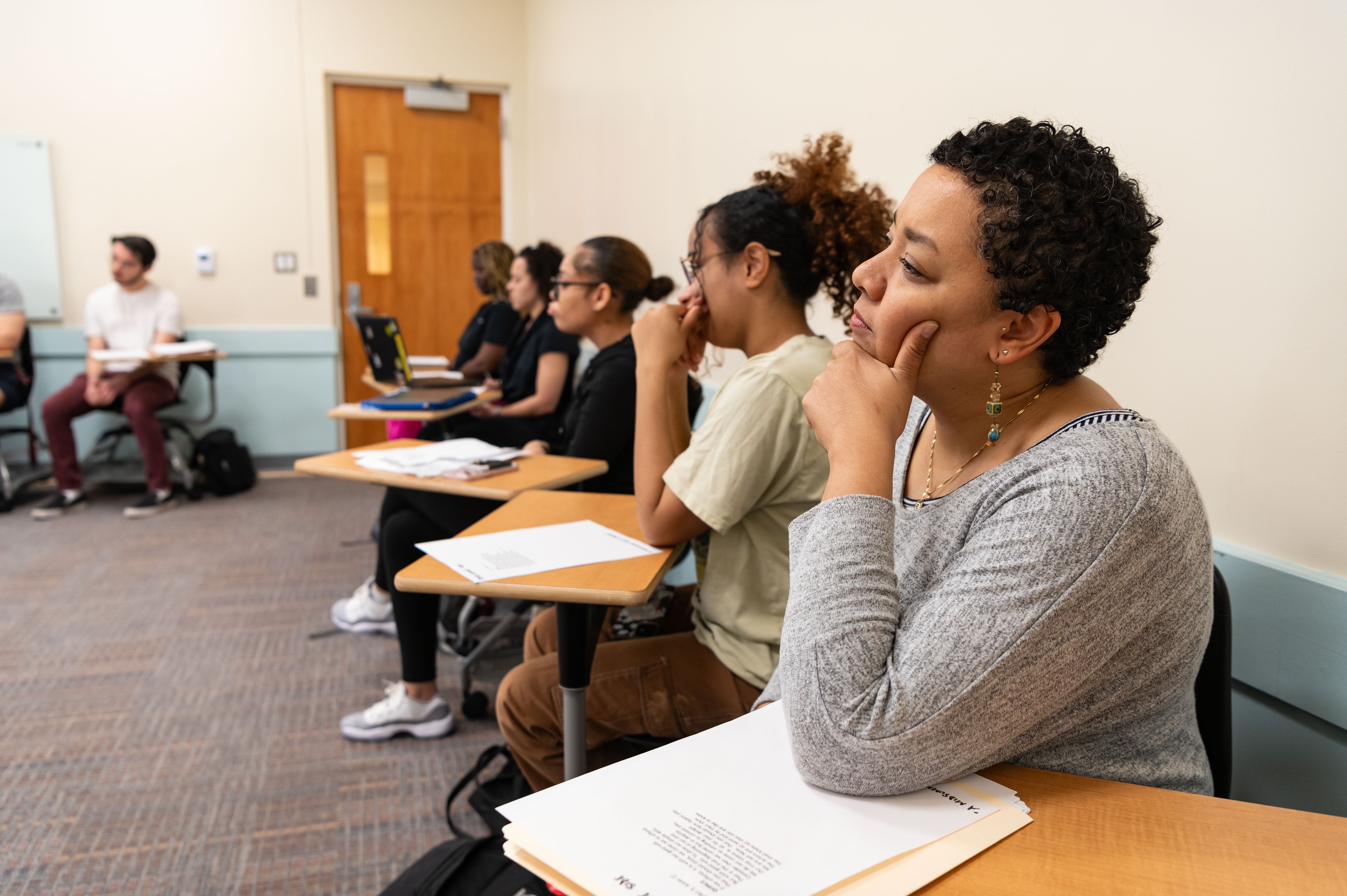 Student thinking in a classroom with other students