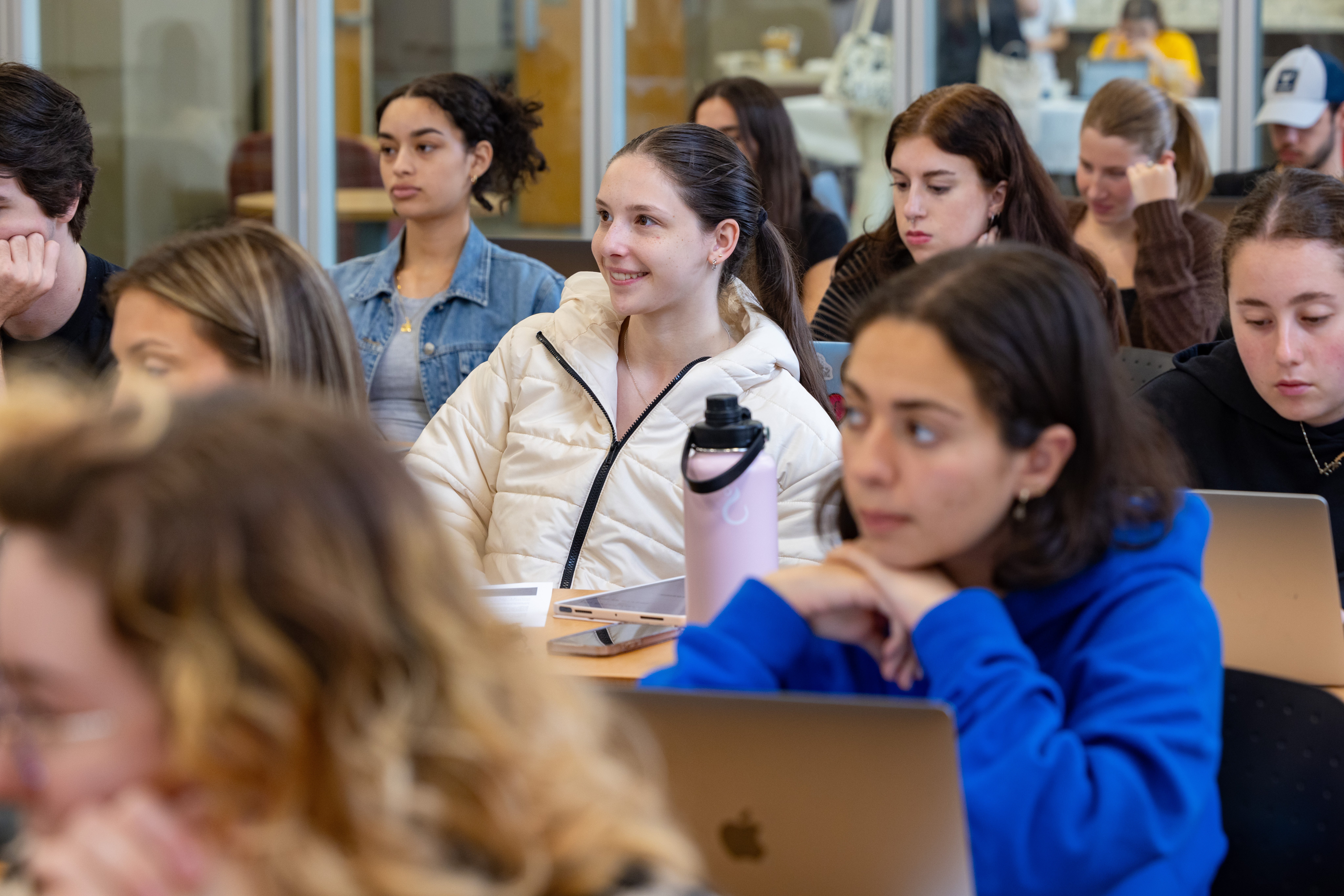 Students in lecture sitting at tables, some with laptops