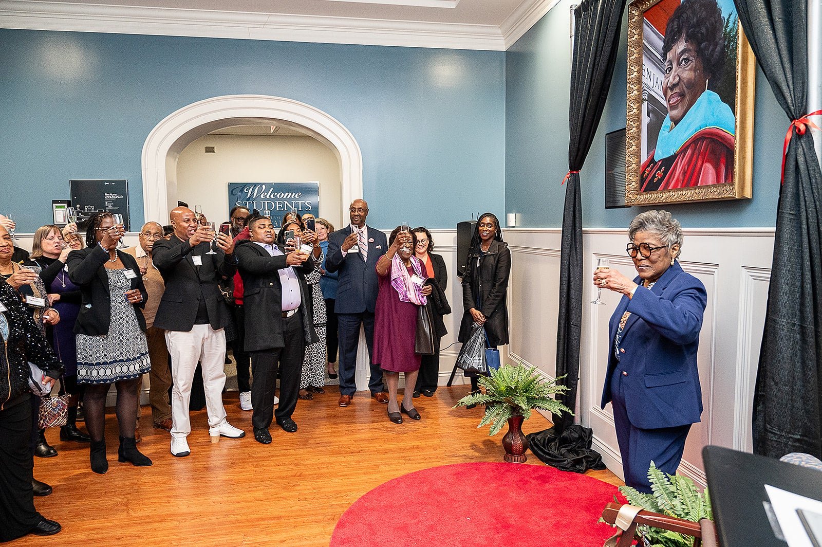 A crowd applauds Elaine Johnson Coates '59 at the unveiling of her portrait in the Benjamin Building