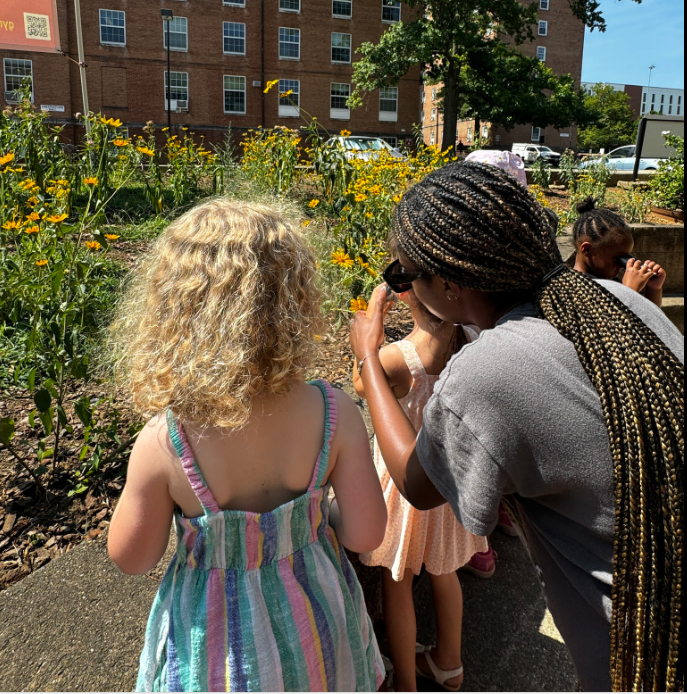 A student intern observes plants with children