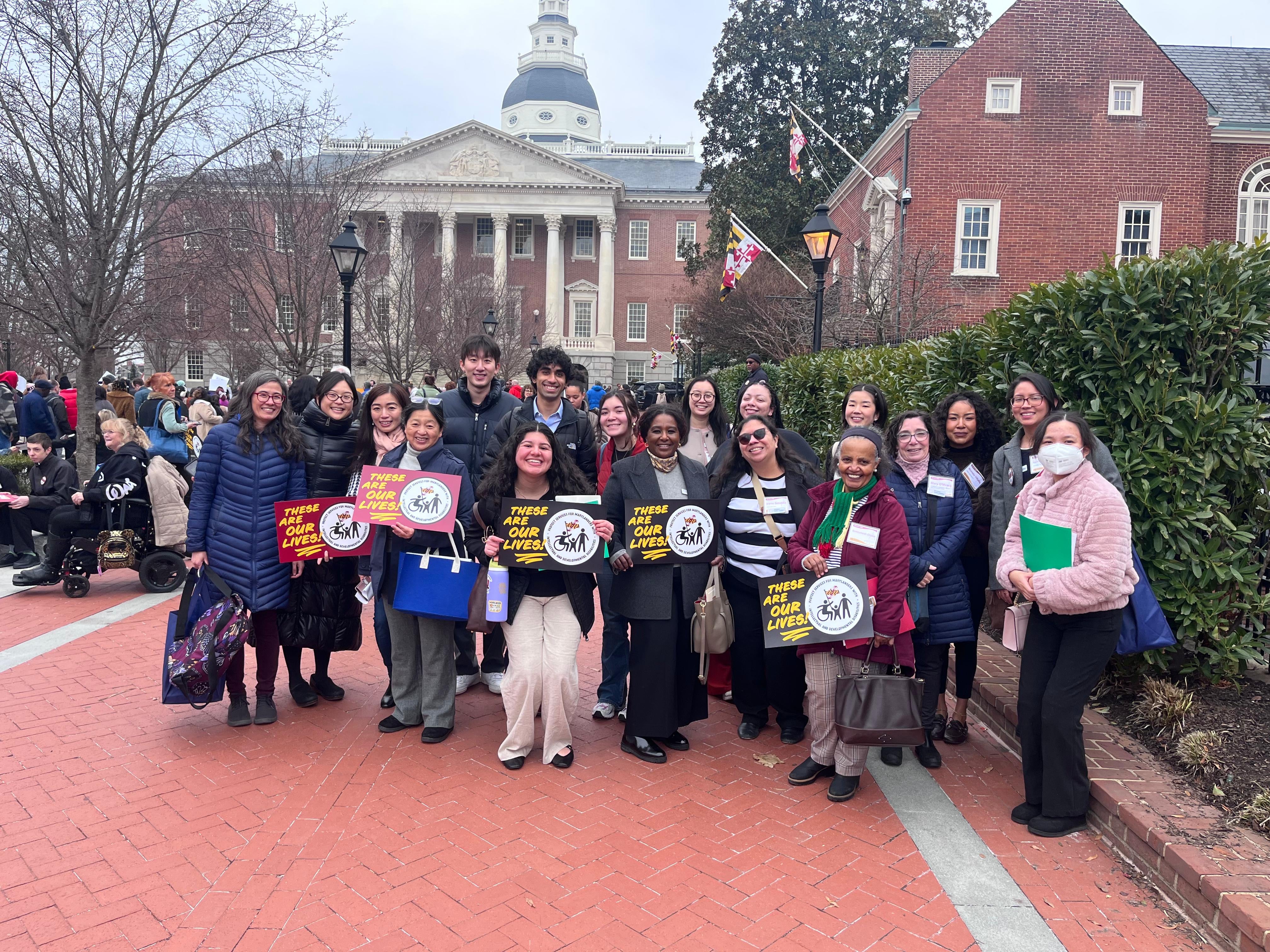 Representatives from the Maryland Equity Coalition for People with Disabilities, including UMD faculty and students, hold signs reading "These Are Our Lives" outside the Maryland State House.