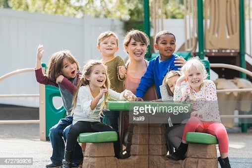 Teacher with children at picnic table.